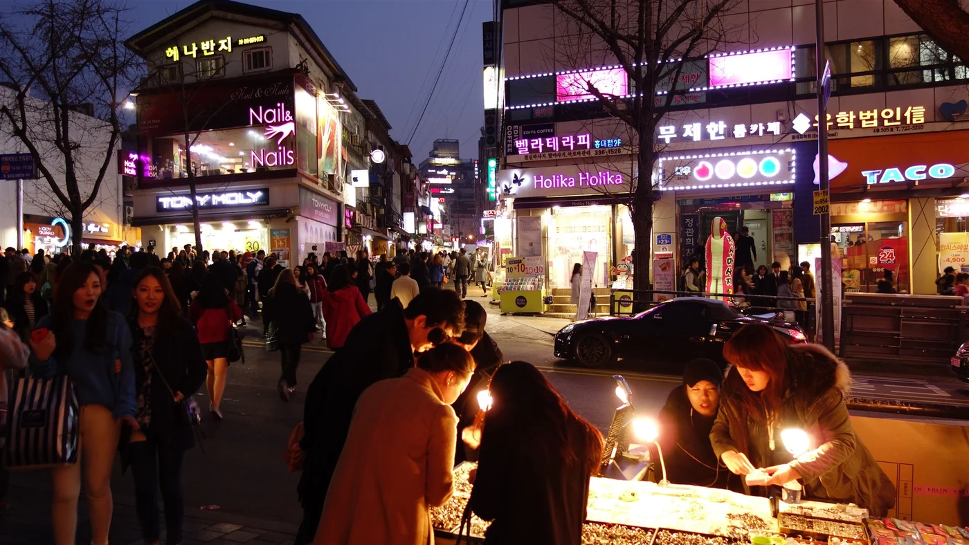 Hongdae nightlife street in Seoul with bright shop signs and evening crowds